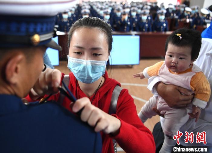 新消防員楊振的妻子彭莉與女兒現(xiàn)場見證丈夫加入“火焰藍”的神圣時刻?！⒅铱?攝