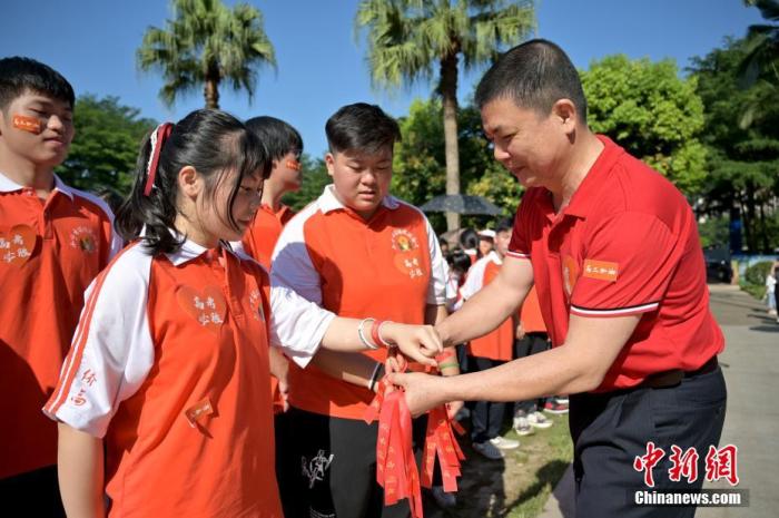 資料圖：廣西華僑實(shí)驗(yàn)高中的教師為高三學(xué)子系上紅絲帶，盼望學(xué)子高考必勝。 俞靖 攝